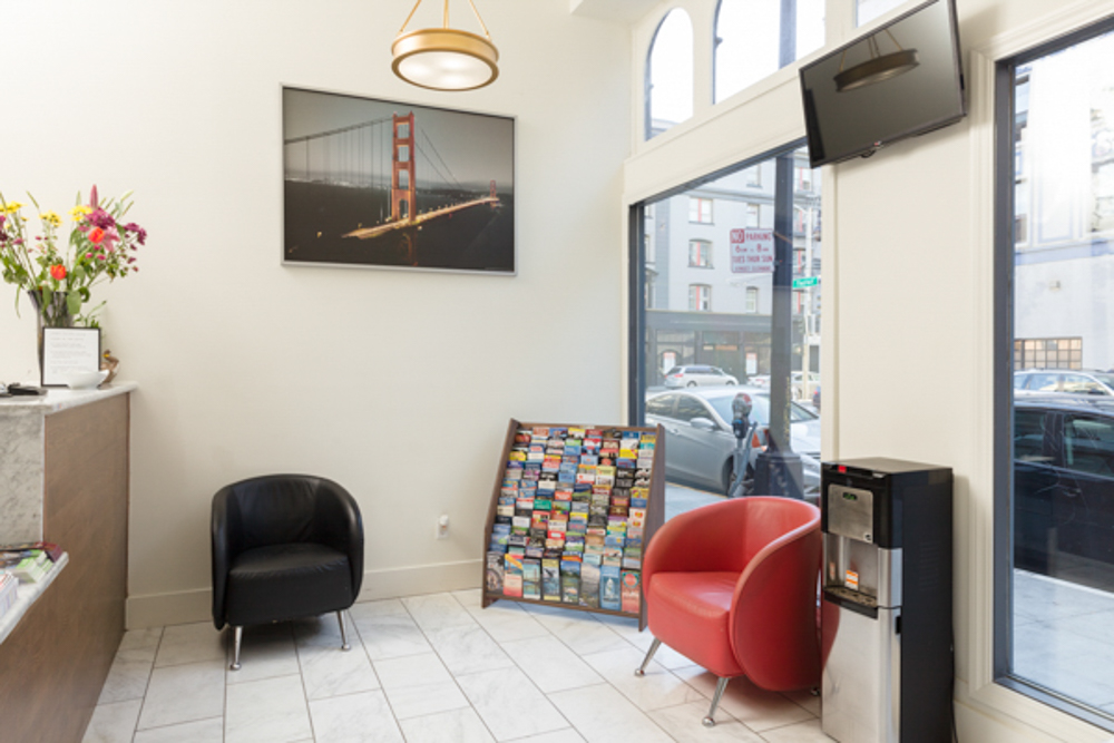 A hotel lobby with two chairs, a water cooler, and a TV on the wall.