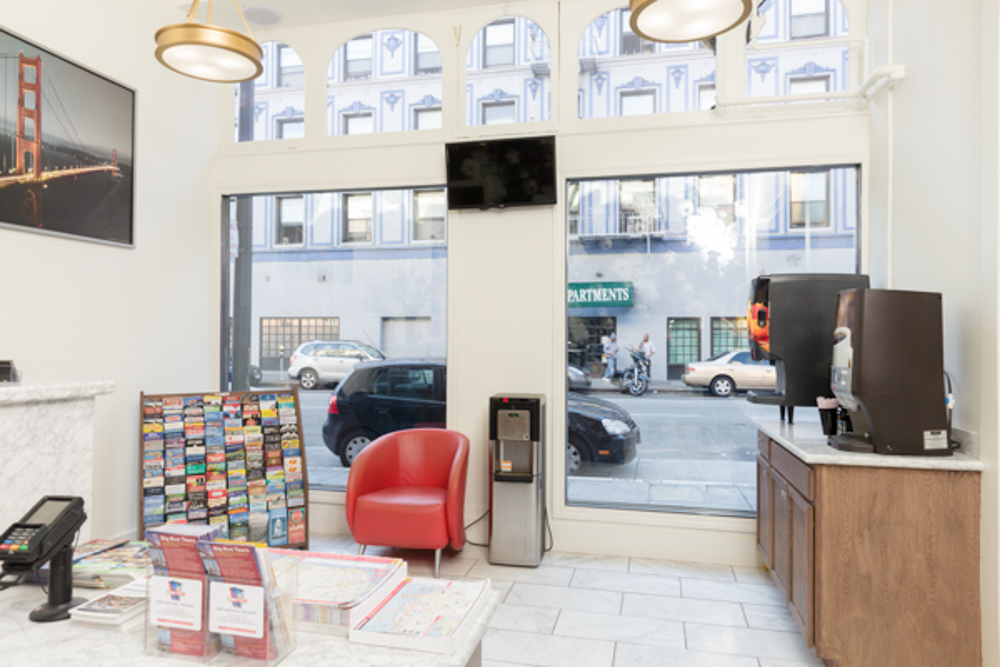 A hotel lobby with a reception desk, a seating area, and a city view.