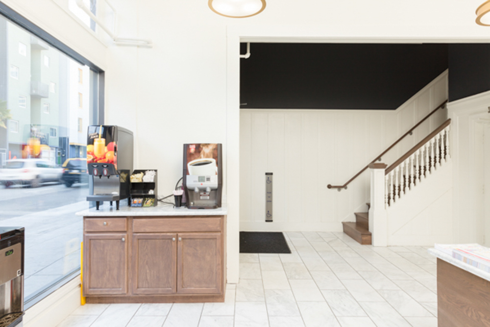 A hotel lobby with a coffee machine, staircase, and counter.