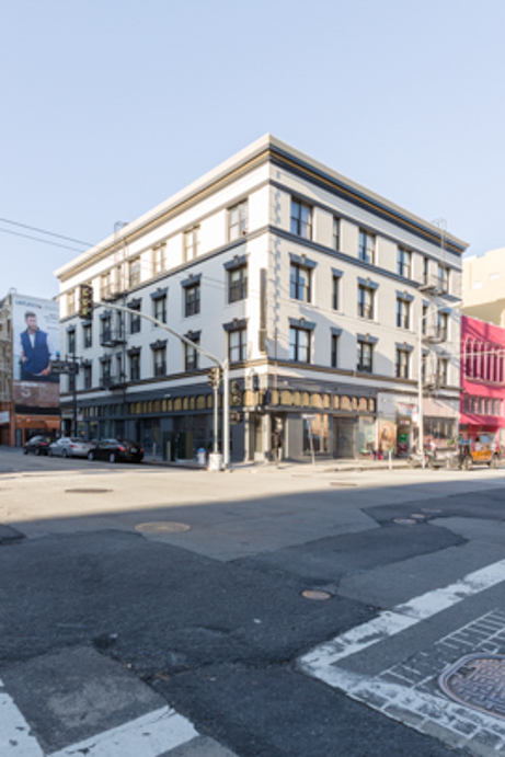 A white, multi-story building with black trim on a street corner.