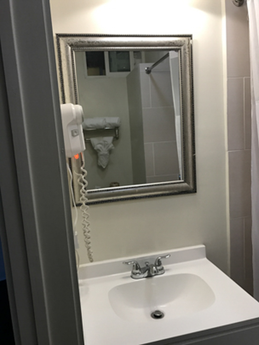 A bathroom sink area with a mirror, shower curtain, and phone.